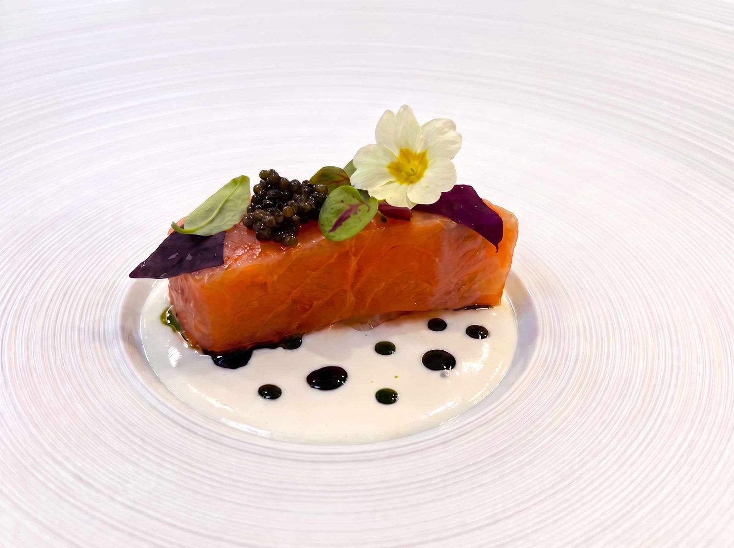 Cured salmon with caviar, micro herbs and a primrose flower on a crème fraîche sauce